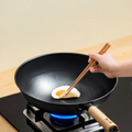 Cooking a fried egg in 30cm Zhang Xiaoquan AU iron wok with chopsticks, demonstrating natural non-stick hammered surface.