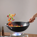 36cm nitrided Chinese wok in action on gas stove, stir-frying vegetables with flames, showcasing heat resistance and cooking performance.