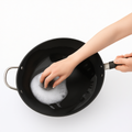 Hand washing 34cm iron wok with soap, highlighting easy maintenance and metal utensil-safe non-stick surface.