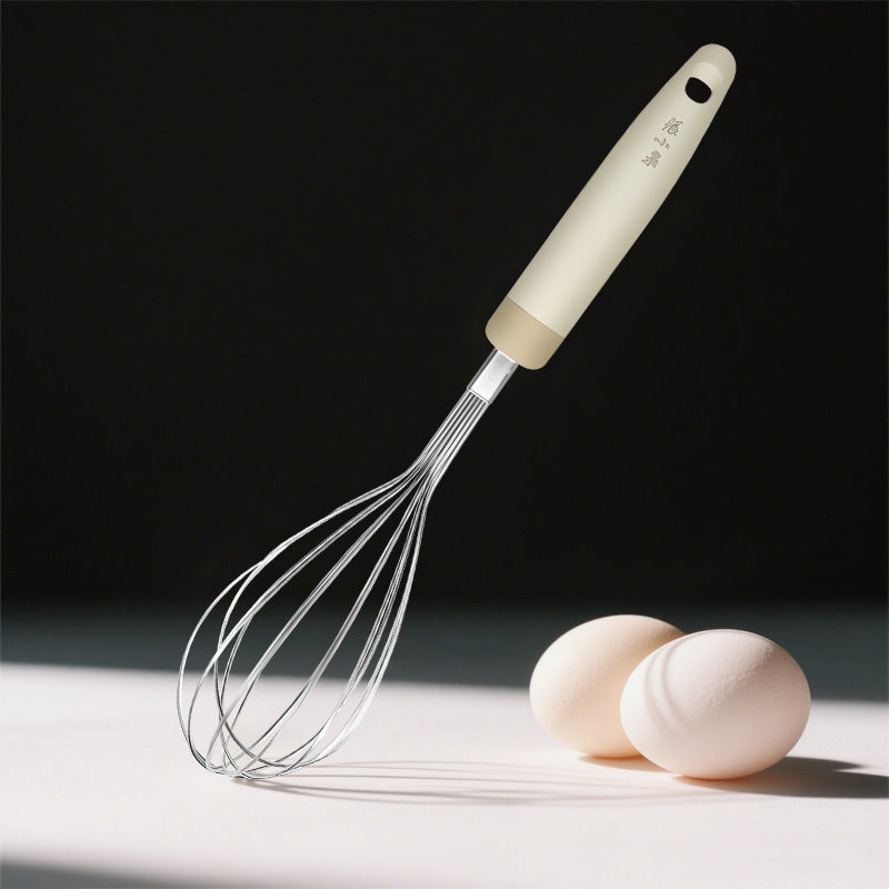 290mm stainless steel whisk with soft grip handle beside eggs, perfect for silent egg whisking and batter mixing.