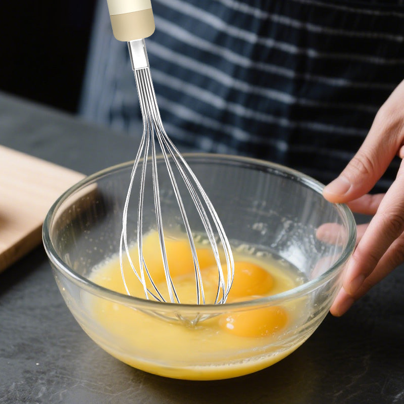 Manual 290mm steel whisk in use mixing eggs in a glass bowl, essential kitchen tool for baking and cooking.