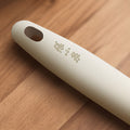 Close-up of the beige ergonomic handle with Zhang Xiaoquan branding, designed for comfort and control in heat-resistant kitchen tools.