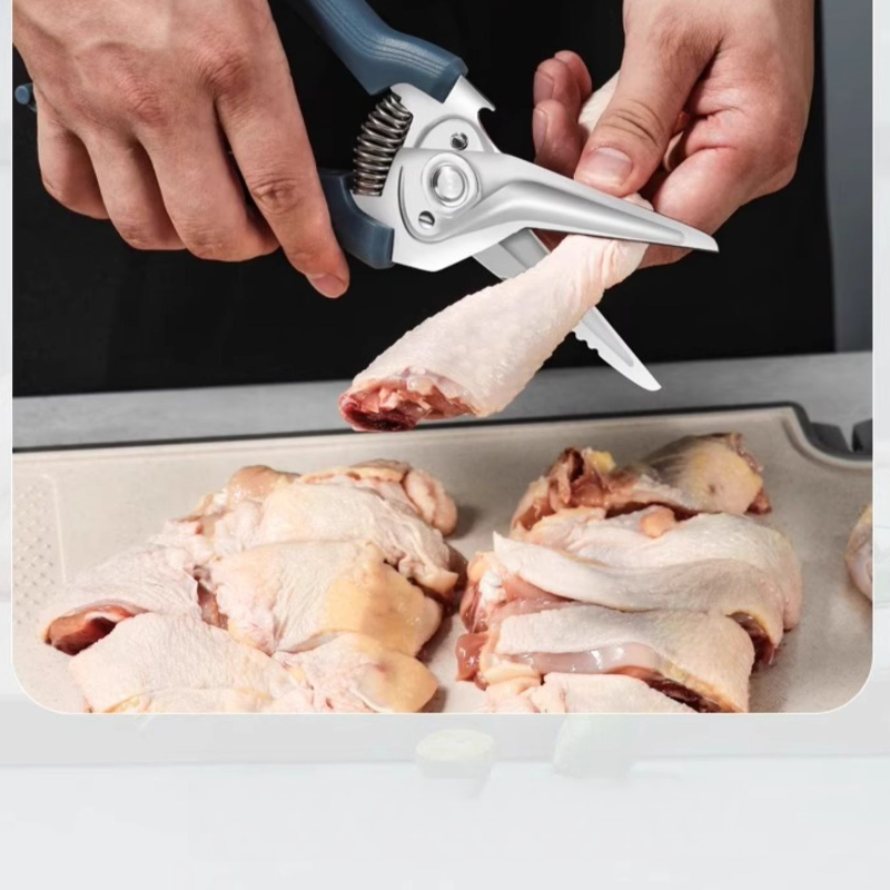 Spring-assisted kitchen shears cutting chicken pieces, ideal for butchering tasks with durable 30Cr13 stainless steel blades.