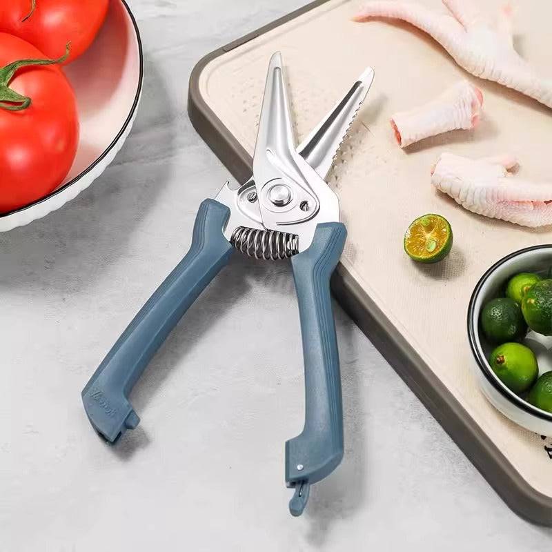 Spring-assist kitchen shears resting on a cutting board with chicken feet and limes, highlighting its versatility in food prep.
