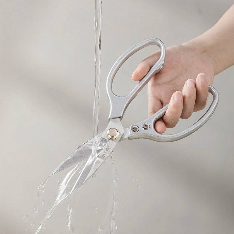 Water-resistant 210mm kitchen scissors being rinsed under running water, highlighting easy cleaning and rust-resistant 40Cr13 stainless steel blades.