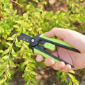 160mm SK5 Steel Pruning Shears in use trimming garden shrub branches, showcasing precision and comfort grip in outdoor setting.