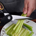 Heavy duty kitchen scissors cutting celery on a plate. Sharp 30Cr13 blades ideal for vegetable prep in home kitchens.