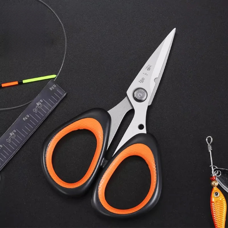 Multi-purpose 110mm fishing scissors with sharp stainless steel blades shown next to fishing tackle, perfect for nylon and PE braid cutting.