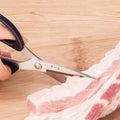 185mm 30Cr13 Multi-Purpose Scissors slicing raw pork, showcasing strength and precision for meat cutting in kitchen use.