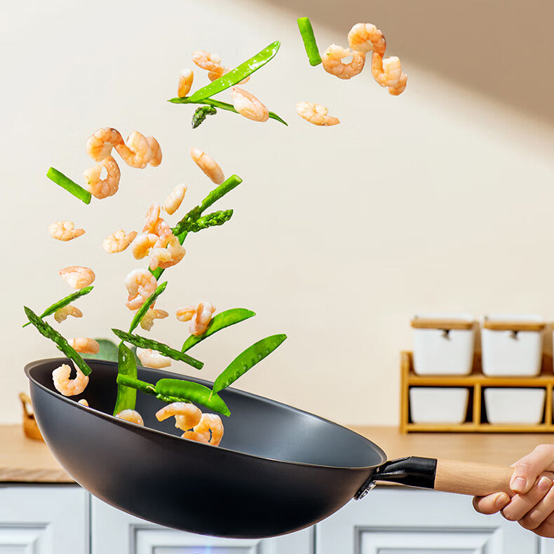 Coating-free iron wok from Zhang Xiaoquan AU tossing shrimp and vegetables mid-air, perfect for healthy high-heat stir-frying.