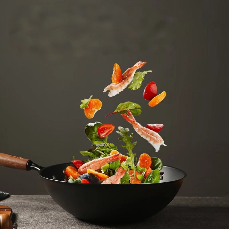 Food ingredients tossed in mid-air above the ShouYi Chinese wok, highlighting its suitability for high-heat stir-frying.