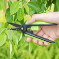 160mm SK5 Steel Pruning Shears trimming green leaves, demonstrating sharp blade performance and ergonomic design for gardening.