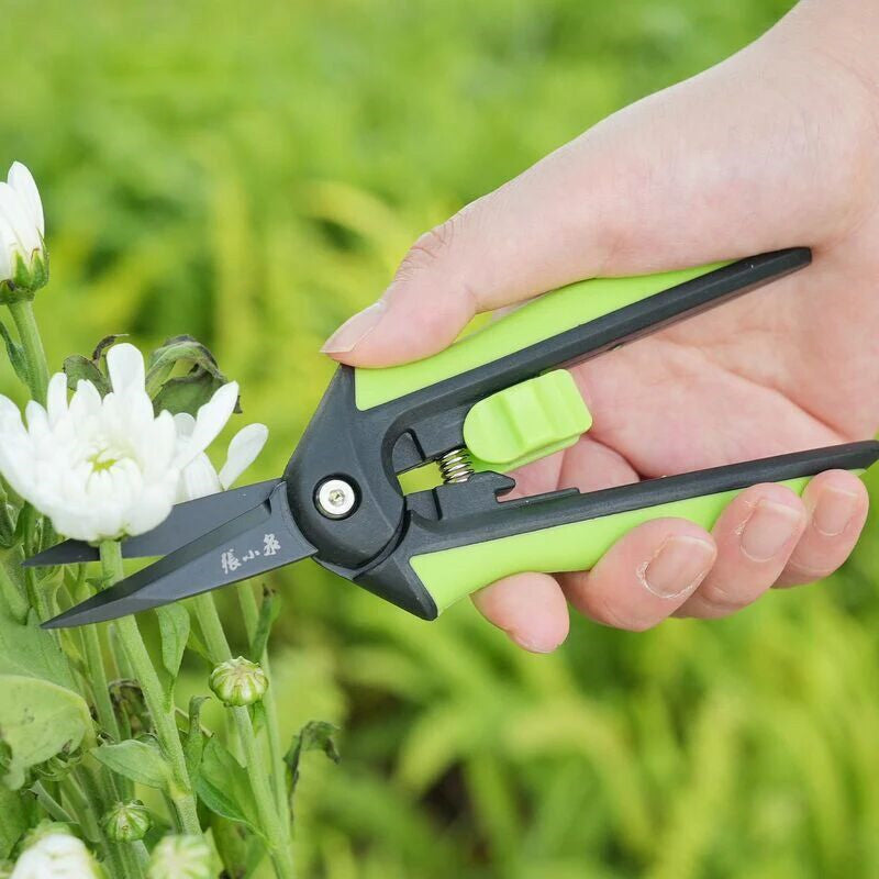 Green-handled 160mm SK5 Steel Pruning Shears cutting white flowers, ideal for delicate garden pruning and floral maintenance.