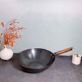 Iron cooking wok displayed on a countertop with decorative elements.