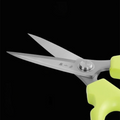 Detailed view of kitchen scissors with ergonomic green handles and sharp blades.