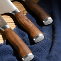 Ergonomic wood handles of 50Cr15MoV steel kitchen knives on a blue cloth.