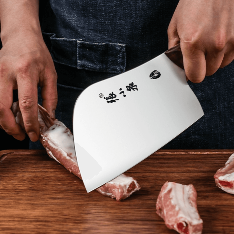 Chinese cleaver cutting raw meat on a wooden board, showcasing sharpness.