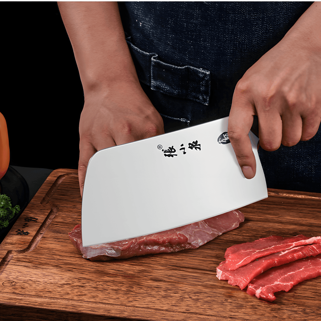 Chinese cleaver slicing raw meat on a wooden cutting board.