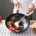 Stainless steel spatula in use for stir-frying vegetables in a wok.