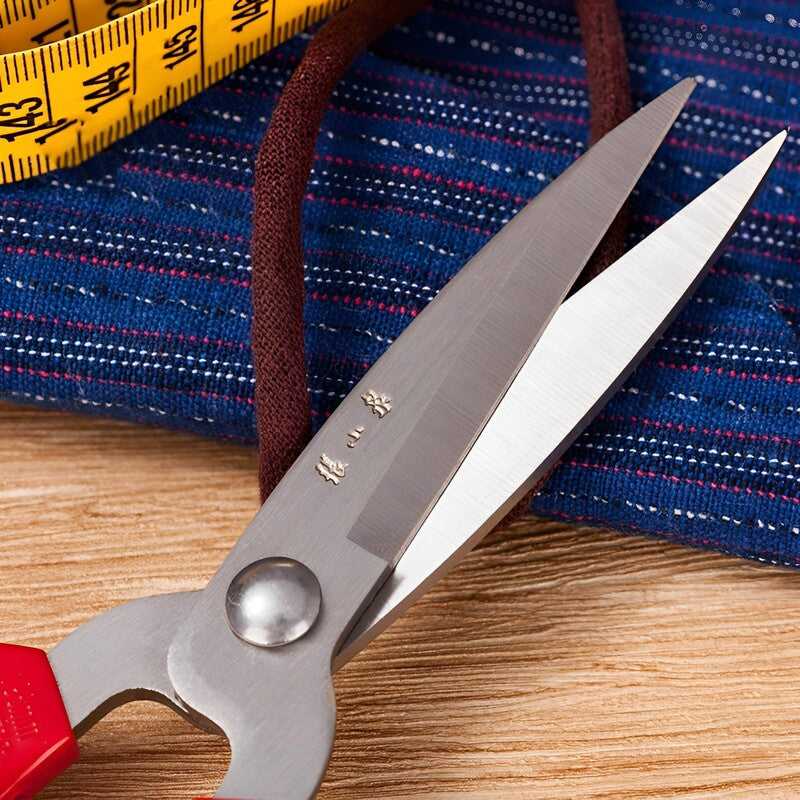 Close-up of stainless steel blades of multi-purpose scissors with red handles.