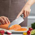 70Cr17MoV Steel Chinese Chef Knife slicing fresh salmon fillet on a cutting board, surrounded by radishes, lime, and parsley. Ideal for precision kitchen tasks.