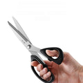 Hand holding ergonomic BBQ shears with sharp stainless steel blades.