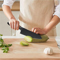 Chef's knife slicing zucchini on wooden cutting board in kitchen setting.