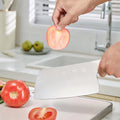 305mm 40Cr13 cleaver slicing a tomato with precision, showcasing its sharp blade and ergonomic white handle.