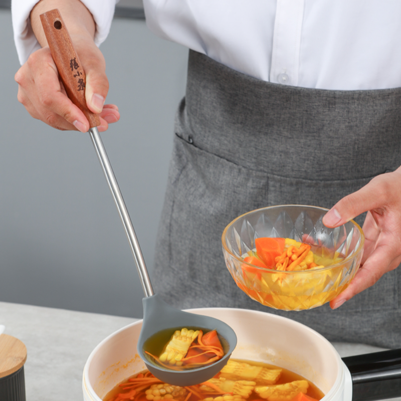 Silicone soup ladle in use, serving vegetable soup from a pot.