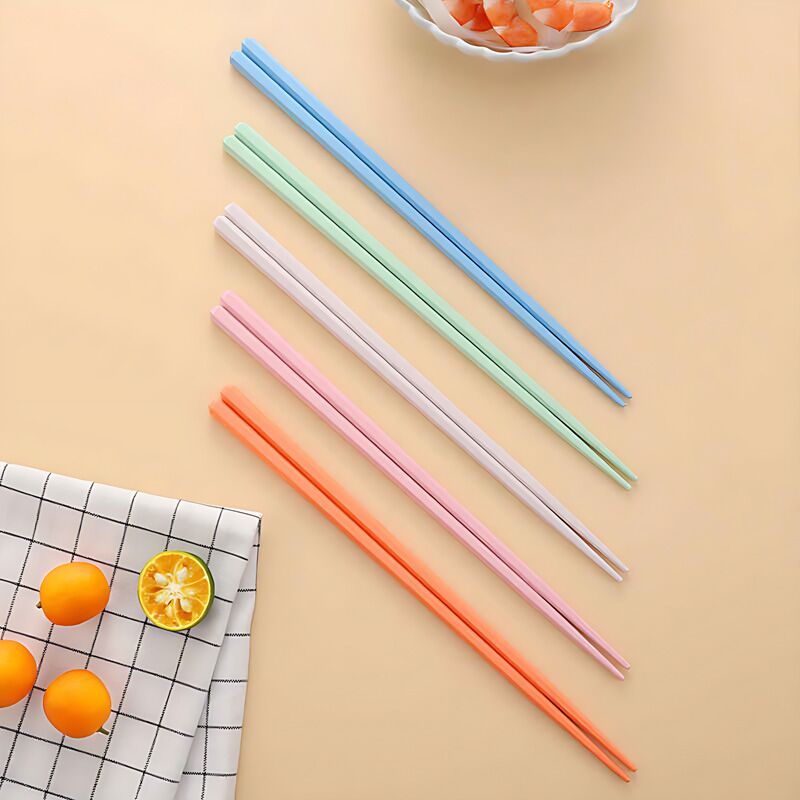 Colorful PET fiber alloy chopsticks displayed on a table with fruits and a grid-patterned cloth.